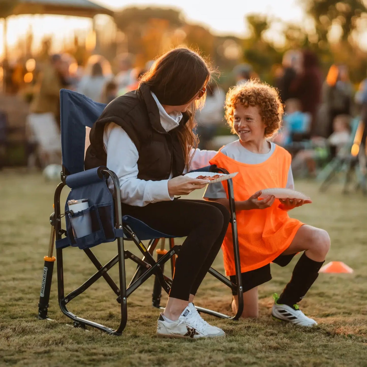 Woman sitting in stowaway rocker while talking to a boy kneeling. 
